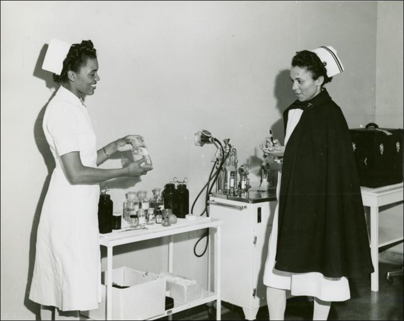 Captain Mary L. Petty Chief Nurse holding a glass bottle and showing it to 2nd Lieutenant Olive Bishop